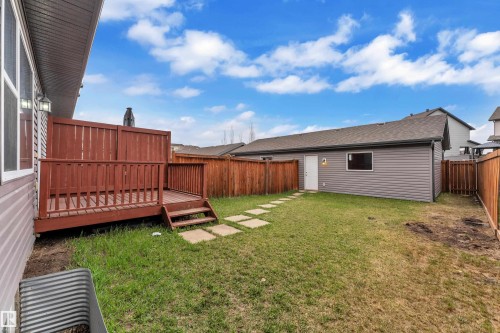 Private backyard featuring a wooden deck with railing, stepping stone pathway, and a detached structure with siding and a window - 2143 32 Street, Edmonton, AB - Outdoor