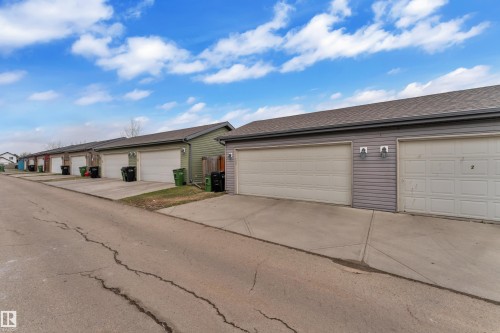 Row of attached garages with white garage doors, asphalt shingle roofing, and concrete driveways - 2143 32 Street, Edmonton, AB - Outdoor
