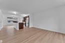 Expansive living area featuring light wood-finish flooring, a kitchen with stainless steel appliances, dark wood cabinetry, a breakfast bar, and recessed lighting - 2143 32 Street, Edmonton, AB  - Indoor 