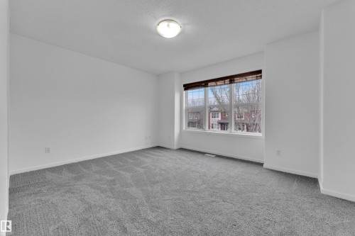 Spacious room with plush gray carpeting, white walls, a large multi-pane window, and a flush-mount ceiling light fixture - 2143 32 Street, Edmonton, AB - Indoor Photo Showing Other Room