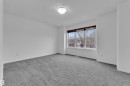 Spacious room with plush gray carpeting, white walls, a large multi-pane window, and a flush-mount ceiling light fixture - 2143 32 Street, Edmonton, AB  - Indoor Photo Showing Other Room 