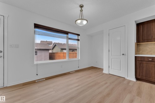 Neutral interior featuring wood-finish flooring, a large window with horizontal blinds, white walls, and a ceiling-mounted light fixture - 2143 32 Street, Edmonton, AB - Indoor Photo Showing Other Room