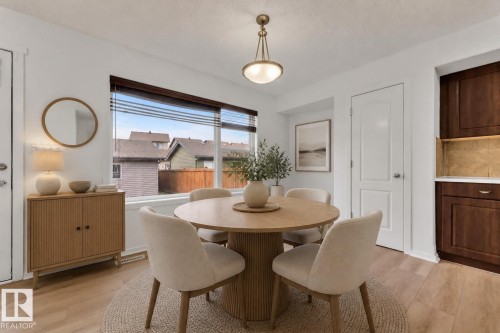 Dining area featuring a large window with horizontal blinds, wood-finish flooring, and a contemporary ceiling light fixture - 2143 32 Street, Edmonton, AB - Indoor Photo Showing Dining Room