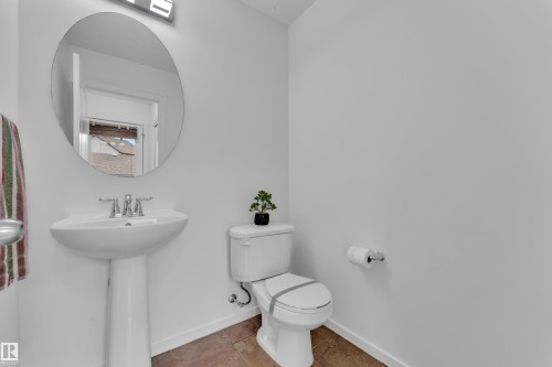 Pedestal sink with chrome fixtures and a circular mirror - 2143 32 Street, Edmonton, AB - Indoor Photo Showing Bathroom