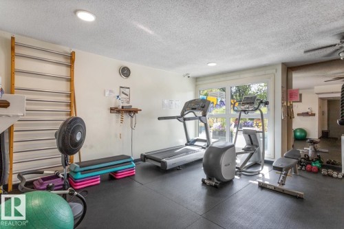 Dedicated fitness room featuring rubber flooring and abundant natural light from the large window.  New Fitness Room is under construction. - 602 12303 Jasper Avenue, Edmonton, AB - Indoor Photo Showing Gym Room
