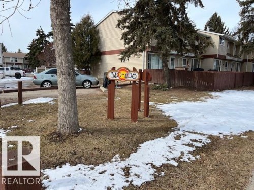The property features a brown wooden fence, a brown wooden sign with property numbers, and a paved parking area - 350 Clareview Road, Edmonton, AB - Outdoor