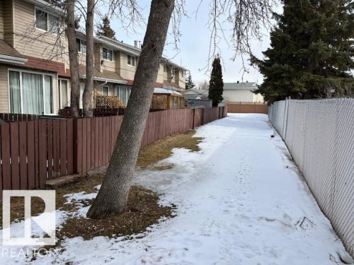 The property features a private fenced yard with a brown wooden fence, a mature tree, and a paved pathway - 350 Clareview Road, Edmonton, AB - Outdoor