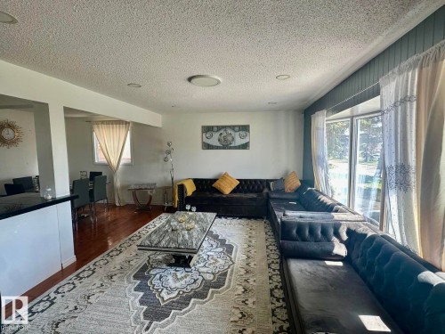 Spacious living area featuring wood-finish flooring, recessed lighting, and large windows - 8620 137 Avenue, Edmonton, AB - Indoor Photo Showing Living Room