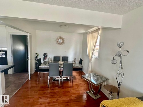 Dining area featuring wood-finish flooring, a wall-mounted light fixture, and a window with natural light - 8620 137 Avenue, Edmonton, AB - Indoor
