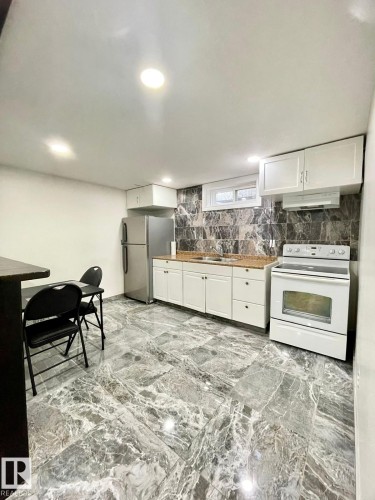 Kitchen area featuring a stainless steel refrigerator, white cabinetry, and a white electric range - 8620 137 Avenue, Edmonton, AB - Indoor Photo Showing Kitchen