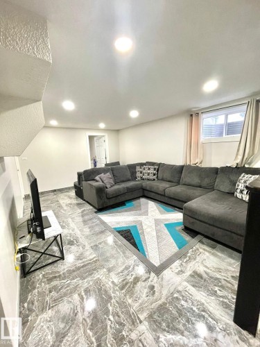 Spacious room featuring large format grey marble-effect tile flooring, recessed ceiling lighting, and light neutral wall finishes - 8620 137 Avenue, Edmonton, AB - Indoor