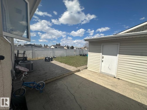 Rear yard featuring a wooden deck, concrete patio, and a detached shed with vinyl siding - 8620 137 Avenue, Edmonton, AB - Outdoor