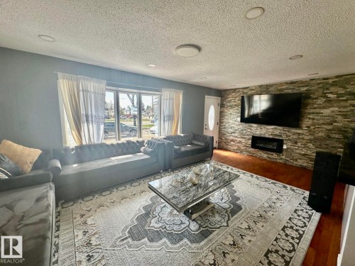 Living area featuring a textured stone accent wall with an integrated electric fireplace - 8620 137 Avenue, Edmonton, AB - Indoor Photo Showing Living Room With Fireplace
