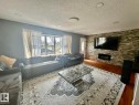 Living area featuring a textured stone accent wall with an integrated electric fireplace - 8620 137 Avenue, Edmonton, AB  - Indoor Photo Showing Living Room With Fireplace 