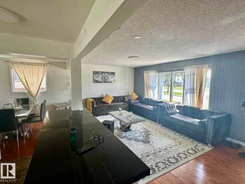 Open-concept living area featuring wood-finish flooring, recessed lighting, and a textured accent wall - 8620 137 Avenue, Edmonton, AB - Indoor Photo Showing Other Room