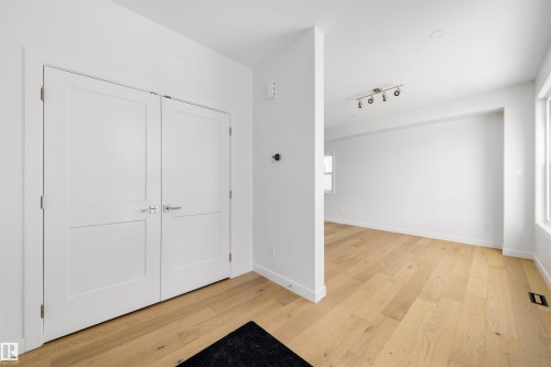 The property features light-toned hardwood flooring, white walls, and bright white trim - 7927 112S Avenue, Edmonton, AB - Indoor Photo Showing Other Room