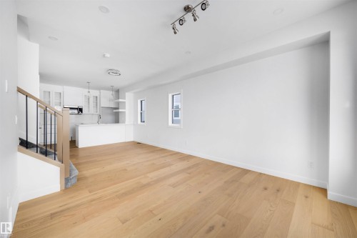 Open concept living space featuring light hardwood flooring, white walls, and a modern kitchen with white cabinetry and stainless steel appliances - 7927 112S Avenue, Edmonton, AB - Indoor Photo Showing Other Room