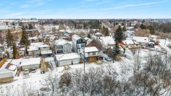 This aerial view showcases the property within a residential setting, featuring various housing styles and an abundance of mature trees - 