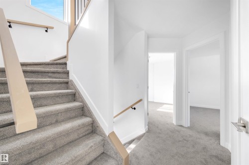 The property features a staircase with carpeted steps and a light-colored wooden handrail, leading to an upper landing with light gray carpet and white walls - 7927 112S Avenue, Edmonton, AB - Indoor Photo Showing Other Room