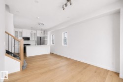 Open-concept living area with wood-finish flooring, recessed lighting, and a modern kitchen - 