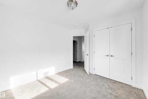 The room features neutral gray carpeting, white walls, and a white double door closet - 7927 112S Avenue, Edmonton, AB - Indoor Photo Showing Other Room