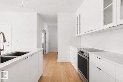 Modern kitchen featuring white cabinetry, light wood-finish flooring, and white countertops - 