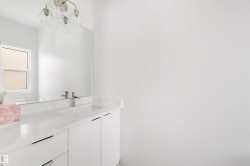 Bathroom featuring a white vanity with drawers and cabinets, a white countertop, and a chrome faucet - 