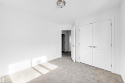 The room features neutral gray carpeting, white walls, and a white double door closet - 