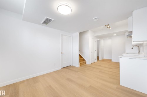 This bright room features light-toned hardwood flooring, white walls, and a modern ceiling light fixture - 7927 112S Avenue, Edmonton, AB - Indoor Photo Showing Other Room