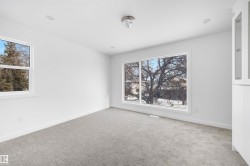 The room features a neutral color palette with light gray carpet and white walls - 
