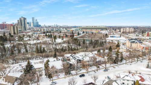 Aerial view showcasing the neighborhood with residential properties, city buildings, and a stadium in the distance - 7927 112S Avenue, Edmonton, AB - Outdoor With View