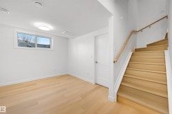 This room features light hardwood flooring, a bright window, and a door with a chrome handle - 