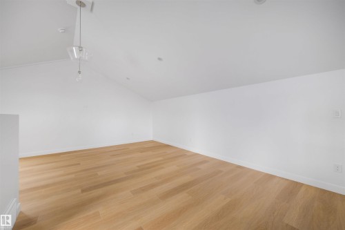 This expansive room features light hardwood flooring, crisp white walls, and a vaulted ceiling with a modern pendant light fixture and recessed lighting - 7927 112S Avenue, Edmonton, AB - Indoor Photo Showing Other Room