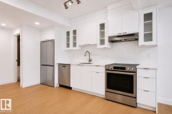 Modern kitchen featuring white cabinetry, stainless steel appliances, light wood-finish flooring, recessed lighting, and a white countertop with a matching backsplash - 