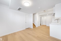 This bright room features light-toned hardwood flooring, white walls, and a modern ceiling light fixture - 