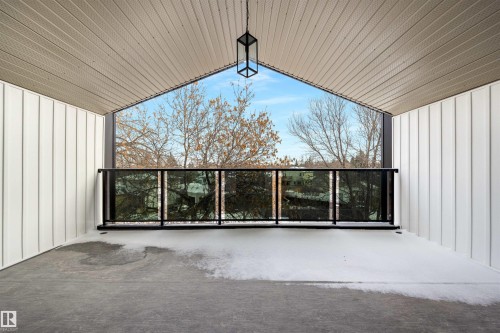 This covered outdoor space features a concrete floor and a modern glass railing, offering views of distant trees and the sky - 7927 112S Avenue, Edmonton, AB - Outdoor With Balcony With Exterior