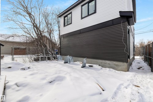 The property features white and dark gray horizontal siding, black trim around the windows, and a concrete foundation - 7927 112S Avenue, Edmonton, AB - Outdoor With Exterior