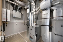 Dedicated utility room featuring a tankless water heater, forced air furnace, and extensive ductwork - 