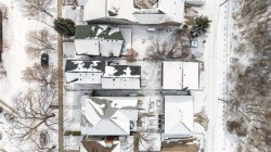 Aerial view of the neighborhood showcasing snow-covered rooftops and mature trees - 