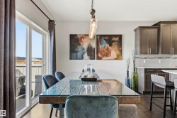 Dining area featuring wood-finish flooring, a contemporary linear chandelier, and sliding glass doors opening to the exterior - 