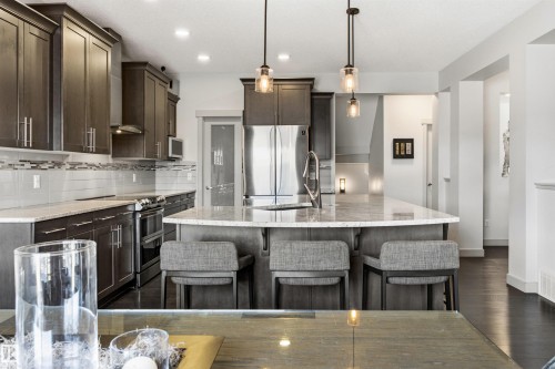 Contemporary kitchen featuring dark wood-finish cabinetry, stainless steel appliances, and a central island with granite countertop. - 7343 Armour Crescent, Edmonton, AB - Indoor Photo Showing Kitchen With Upgraded Kitchen