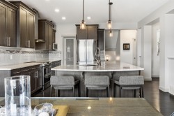 Contemporary kitchen featuring dark wood-finish cabinetry, stainless steel appliances, and a central island with granite countertop. - 