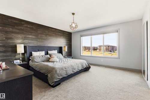 Spacious room featuring a prominent wood-finish accent wall, large window with expansive outdoor scenery. - 7343 Armour Crescent, Edmonton, AB - Indoor Photo Showing Bedroom
