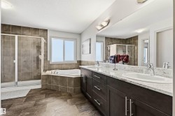 Bathroom featuring a full-width mirror, granite top vanity with two sinks, and a large soaker tub. - 
