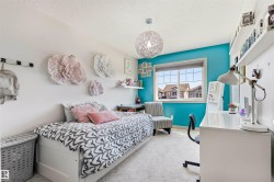 Bright interior room featuring a large window, light-colored carpeting, a contemporary spherical pendant light fixture, and built-in wall shelving - 