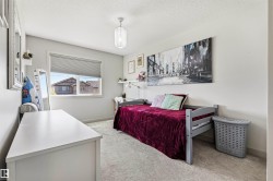 Bright room featuring a single window with blinds, light gray wall paint, textured ceiling, light-colored carpeting, and a ceiling-mounted light fixture - 