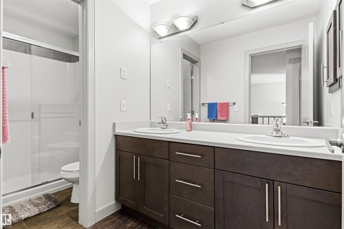 Upper level bathroom featuring a dual vanity with dark wood-finish cabinetry, white countertops, and undermount sinks - 7343 Armour Crescent, Edmonton, AB - Indoor Photo Showing Bathroom