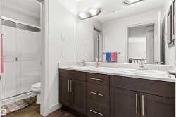 Upper level bathroom featuring a dual vanity with dark wood-finish cabinetry, white countertops, and undermount sinks - 