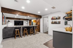 Finished basement featuring a built-in bar with seating, recessed lighting, and a wood-finish barn door - 