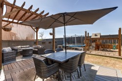 Expansive outdoor living area featuring a wood pergola with shade covering, a spacious deck, and a dining area  with gas hook-up for bbq. - 